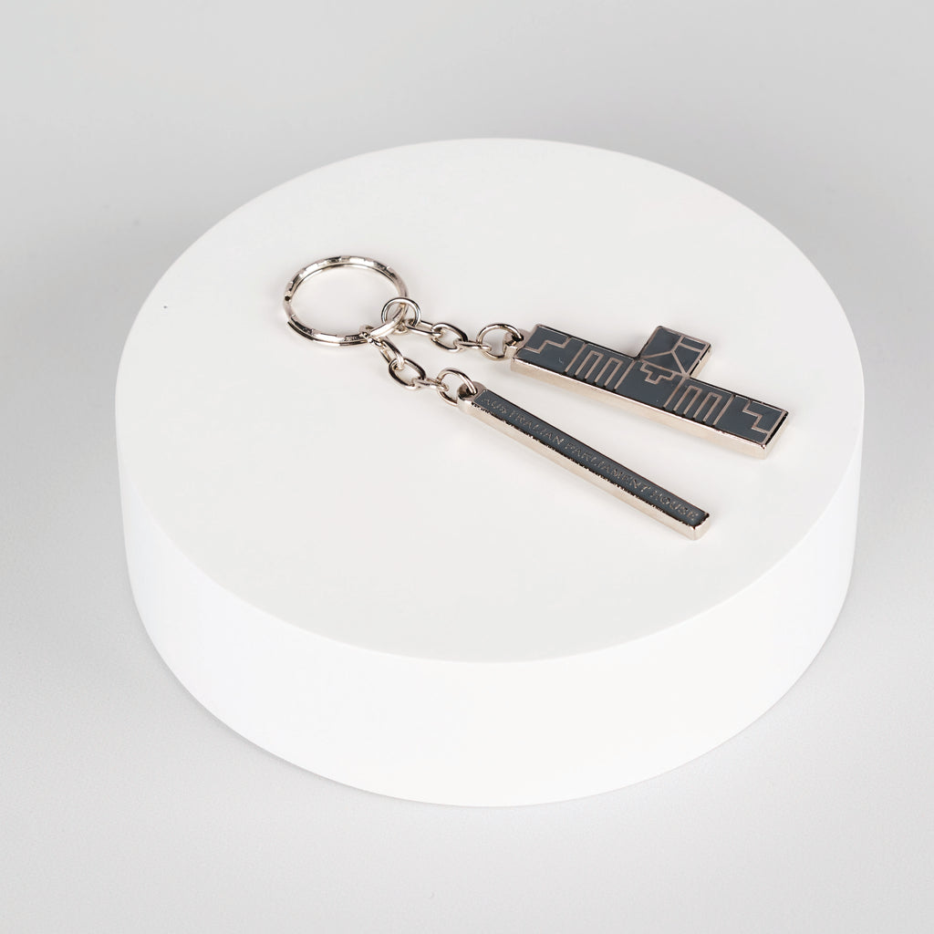silver abstract keychain on top of white circle display