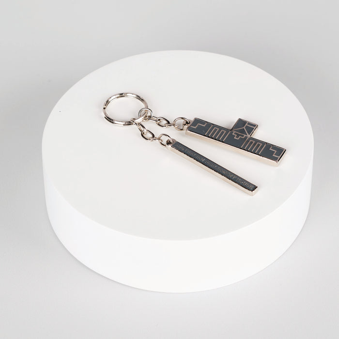 silver abstract keychain on top of white circle display