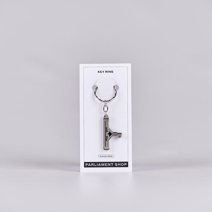 Silver and grey coloured key ring in the shape of Australian Parliament House on a white backing card.