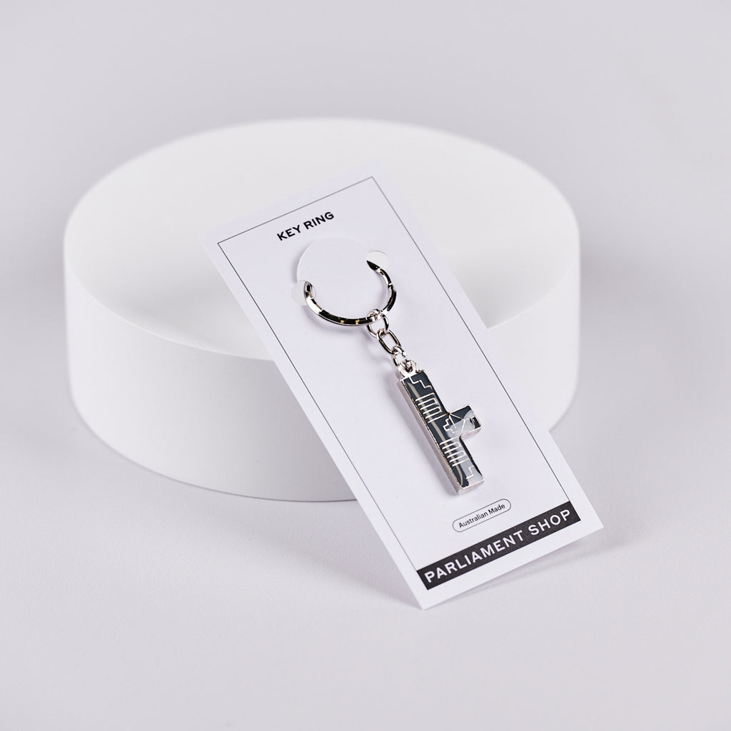 Silver and grey coloured key ring in the shape of Australian Parliament House on a white backing card.