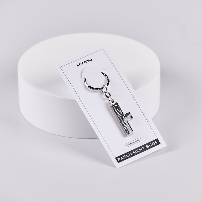 Silver and grey coloured key ring in the shape of Australian Parliament House on a white backing card.