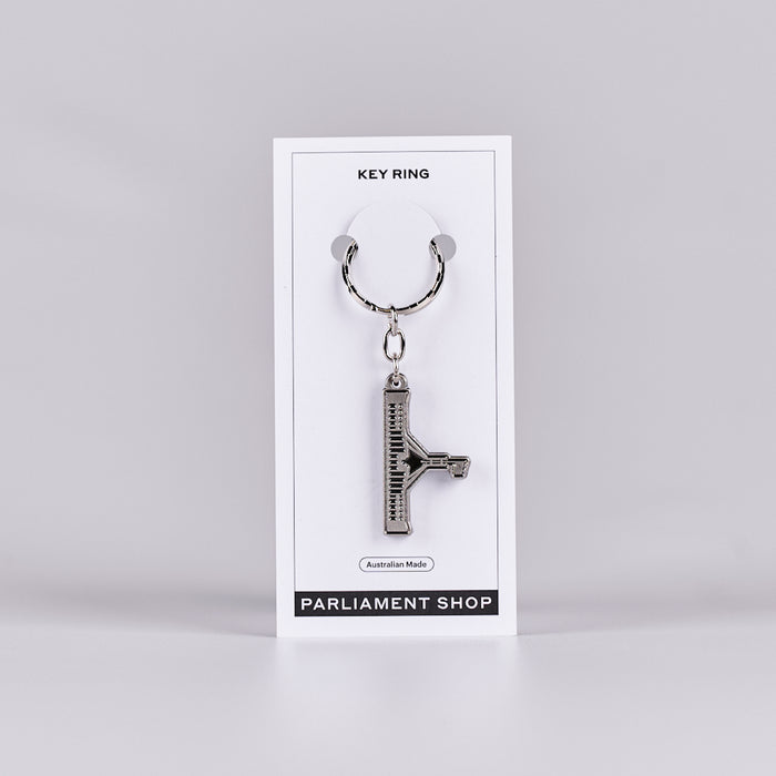 Silver and grey coloured key ring in the shape of Australian Parliament House on a white backing card.