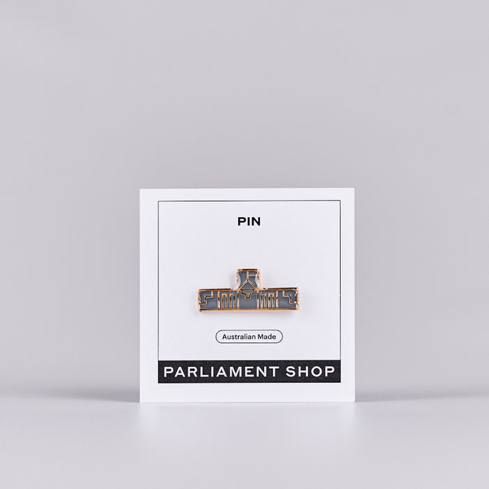 Gold and grey coloured pin in the shape of Australian Parliament House on a white backing card.