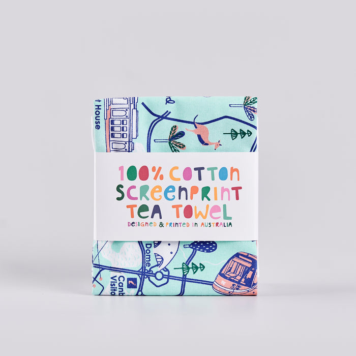 Folded blue and pink tea towel with illustrations of Canberra locations and the word 'Canberra'.