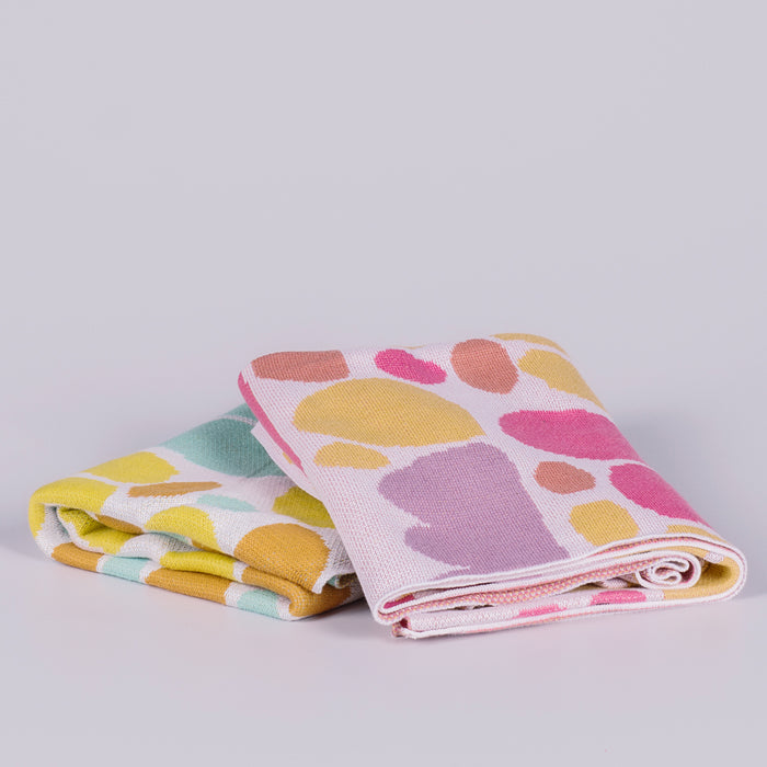Two folded blankets featuring coloured shapes.
