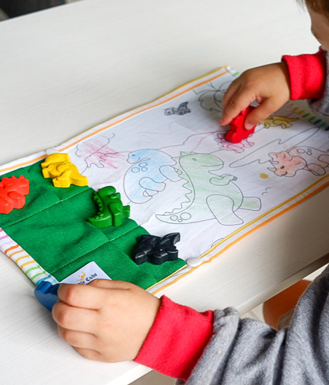 A child colouring in with dinosaur shaped crayons. 