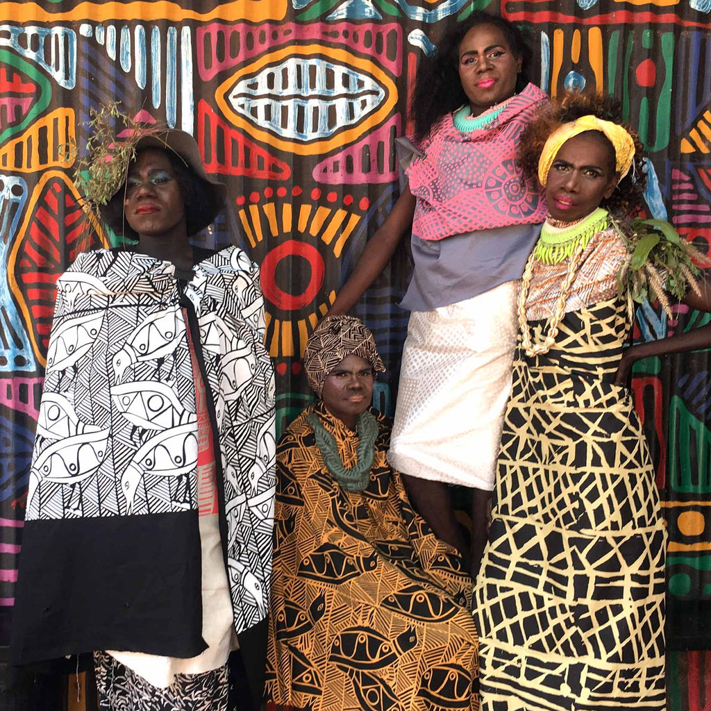 Three women wearing tiwi design patterned fabric. 