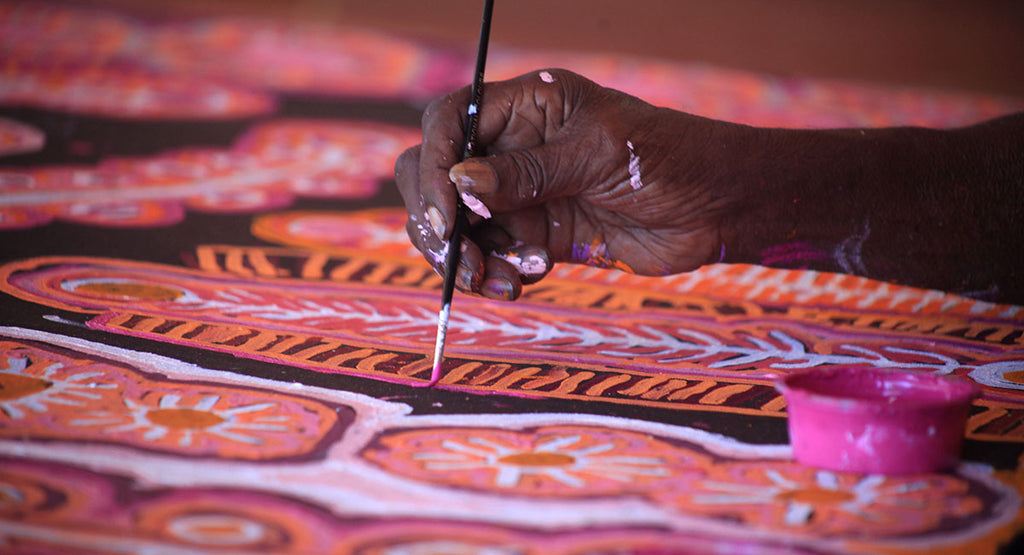 Close up of an Indigenous artists hand painting on a canvas