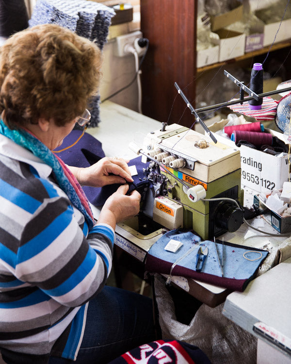 A woman from Otto and Spike using a sewing machine with purple fabric