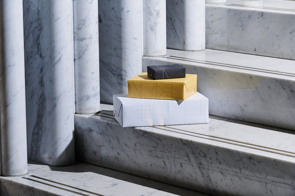 Stack of three gift wrapped boxes in white, yellow and black on the marble staircase at Parliament House.