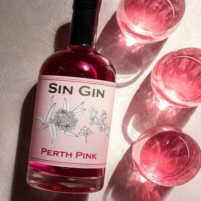 flat lay of perth pink gin (700ml) alongside three glasses filled with pink liquid