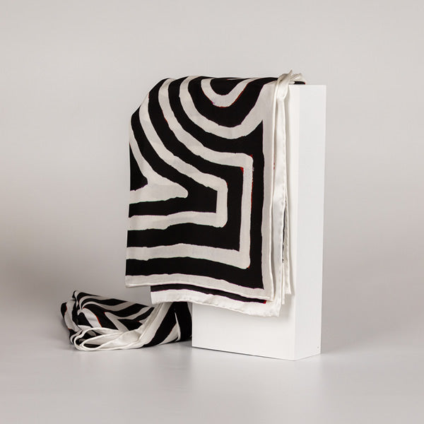black and white silk scarf with stripe pattern hanging from plinth