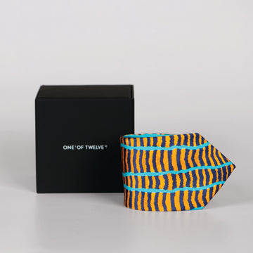 a rolled orange, dark blue and turquoise tie featuring uneven line design and a black display box