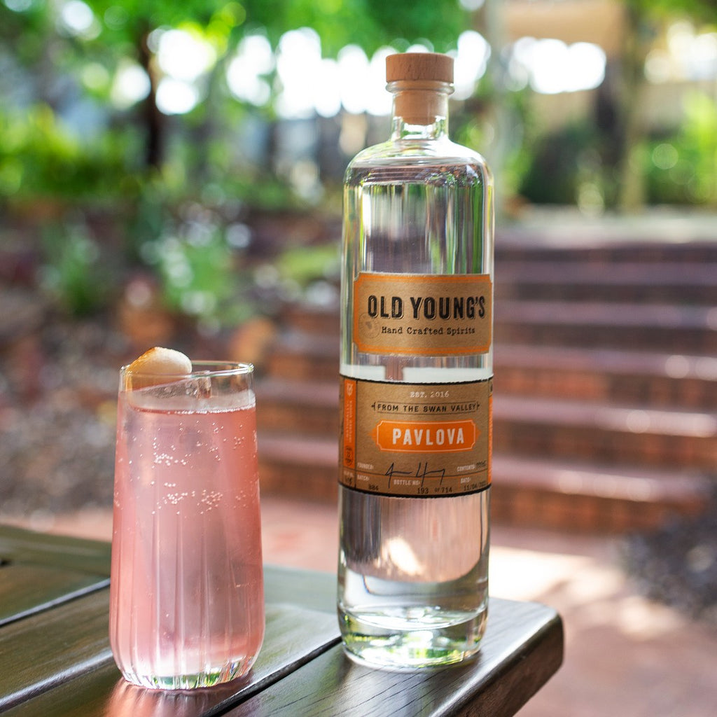 Bottle of Pavlova vodka alongside clear pink iced drink on a table