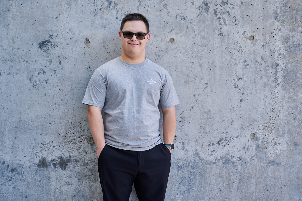 Man wearing a light grey t-shirt with the Parliament House logo on it and the words 'Canberra'.