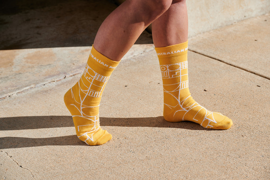 Yellow socks with a white geometric design on a pair of women's feet.