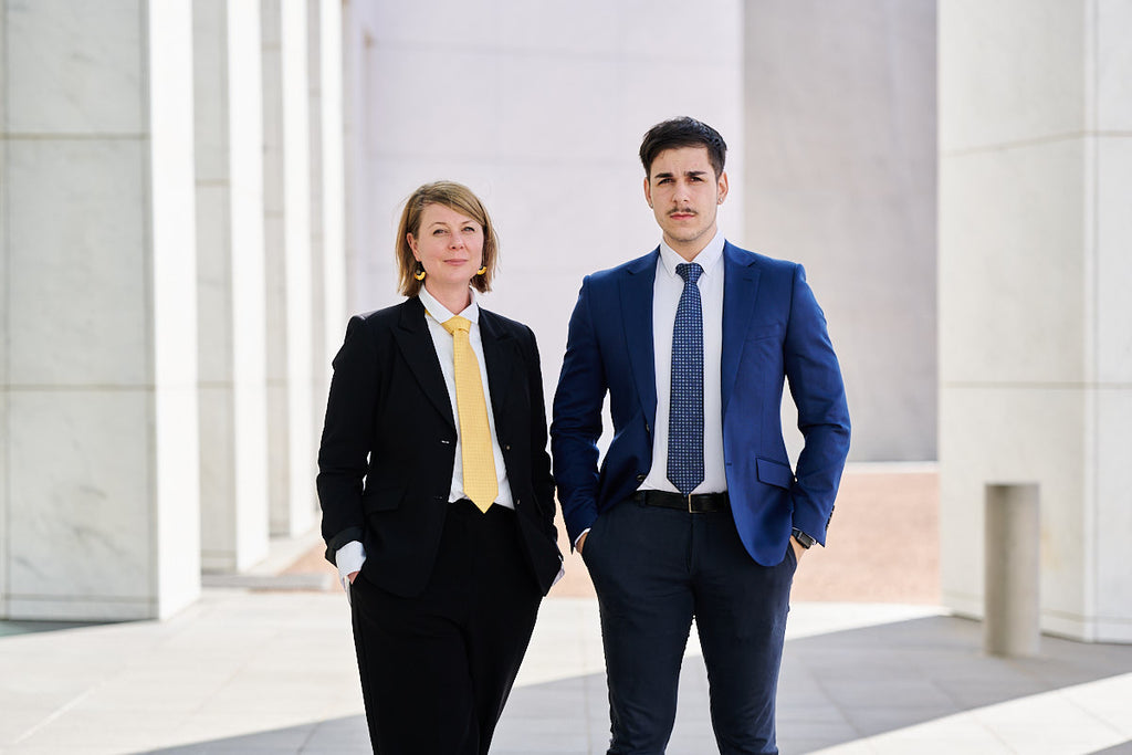 Man and woman next to each other wearing suits and a tie 