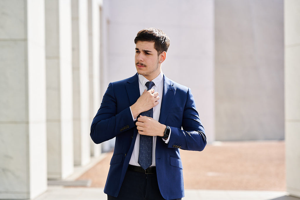man wearing a navy blue suit and tie standing 