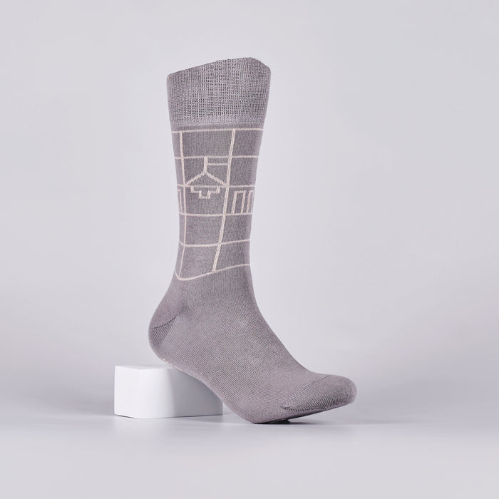 Grey sock with a white geometric design on a foot mannequin.