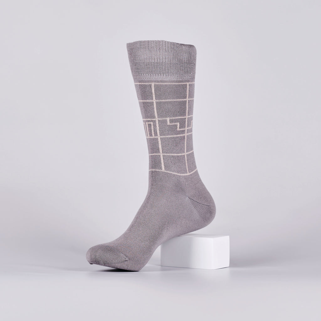 Grey sock with a white geometric design on a foot mannequin.