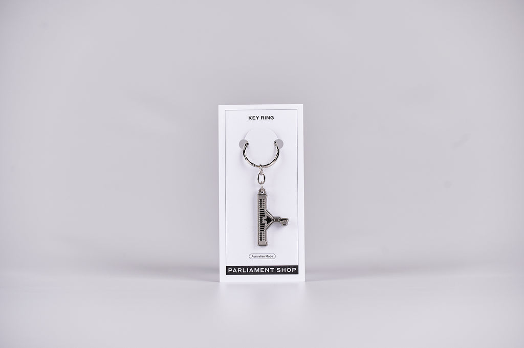 Silver and grey coloured key ring in the shape of Australian Parliament House on a white backing card.