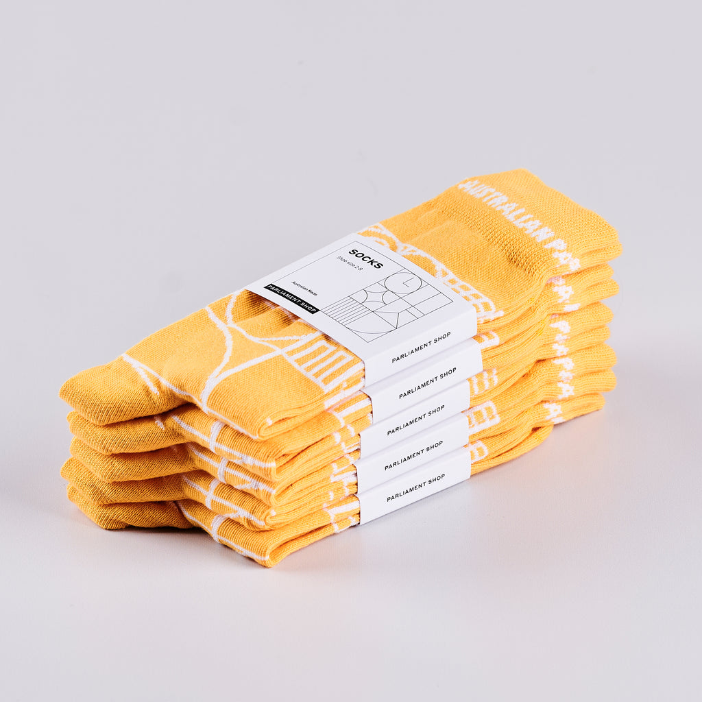 Five pairs of packaged yellow socks in a pile.