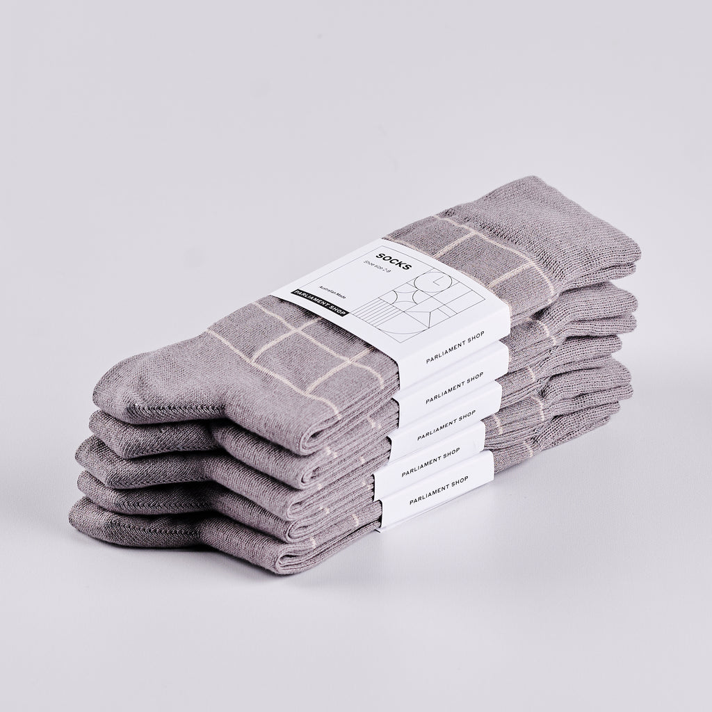 Five pairs of packaged grey socks in a pile.