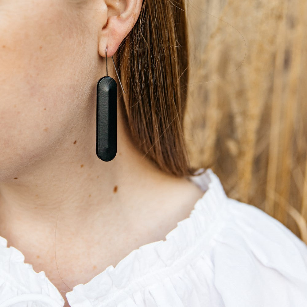 woman wearing Dangle earrings featuring long black oval pendants