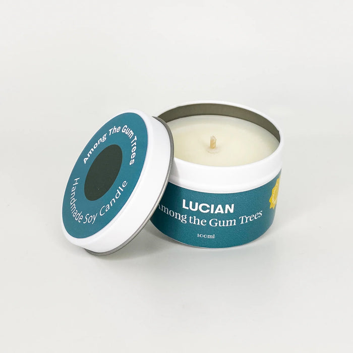 100 ml candle in a teal tin with the words reading 'Lucian Among the Gum Trees' on the label