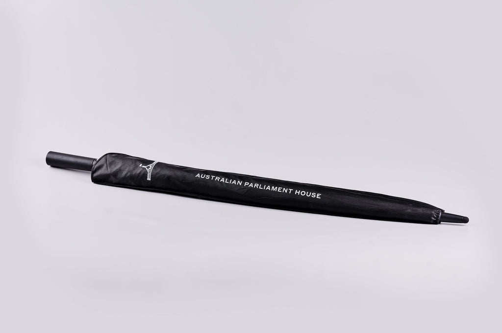 Closed black umbrella in bag with Parliament House logo and text reading 'Australian Parliament House'.