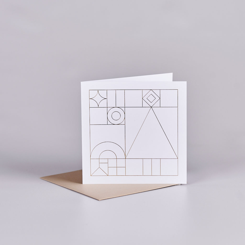 White card with a gold geometric design sitting on a gold envelope.