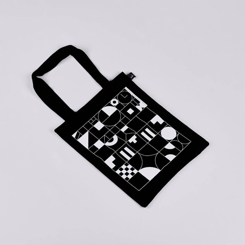 Black tote bag featuring a black and white geometric design. 