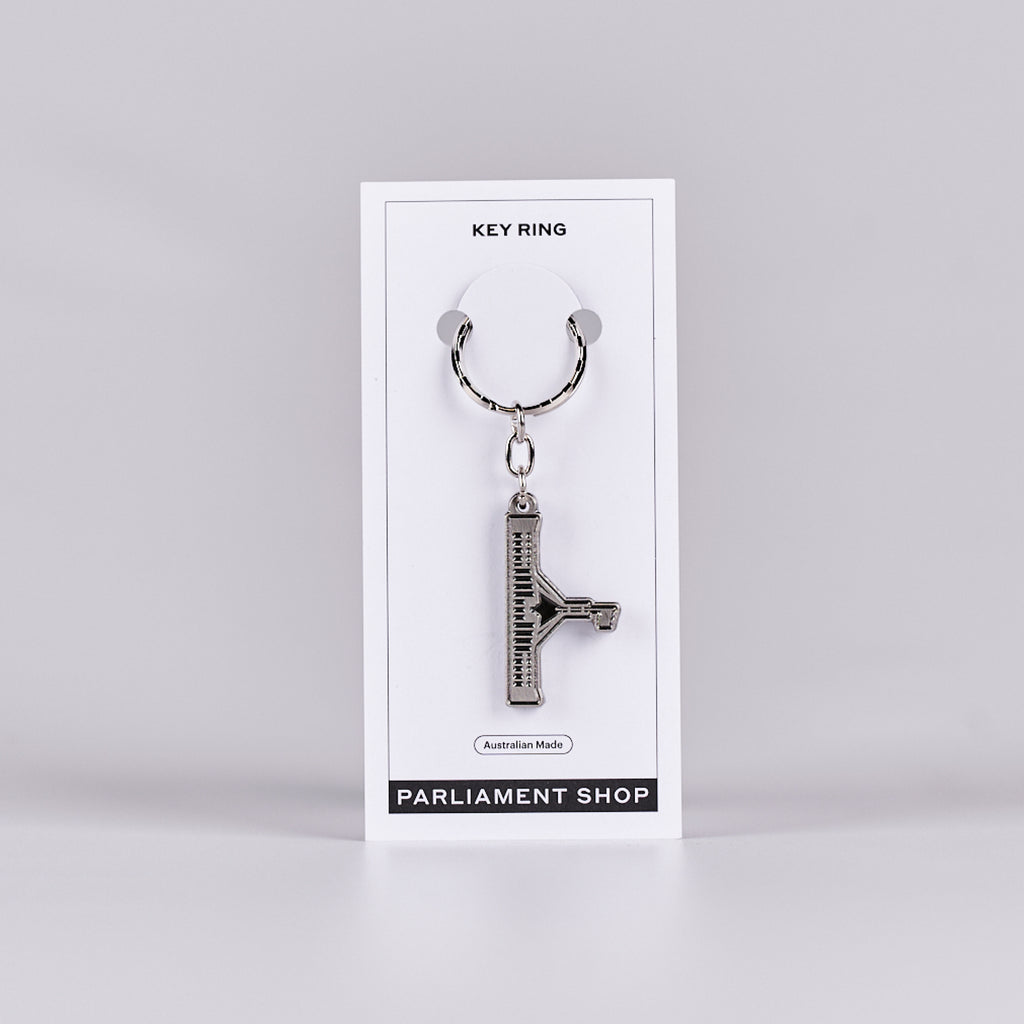 Silver and grey coloured key ring in the shape of Australian Parliament House on a white backing card.