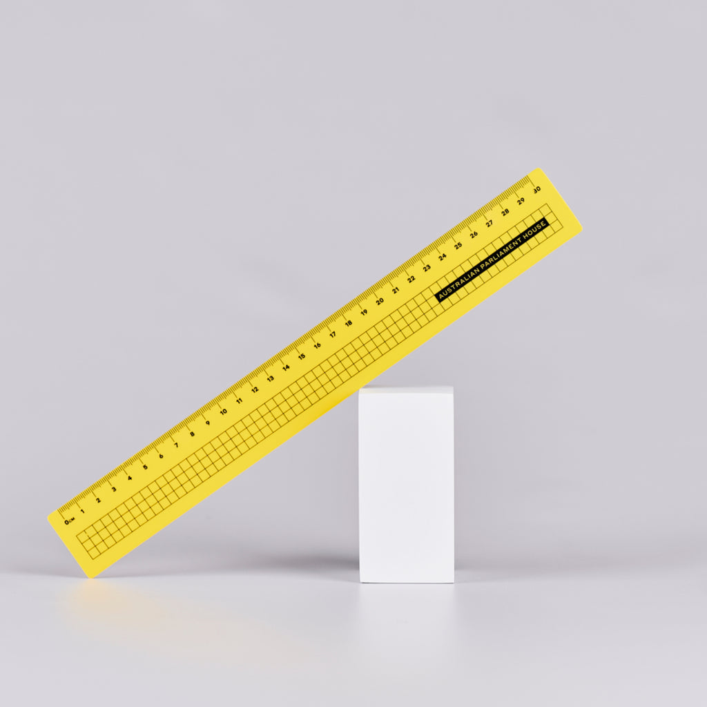 Yellow ruler with a black grid design and text reading 'Australian Parliament House'.