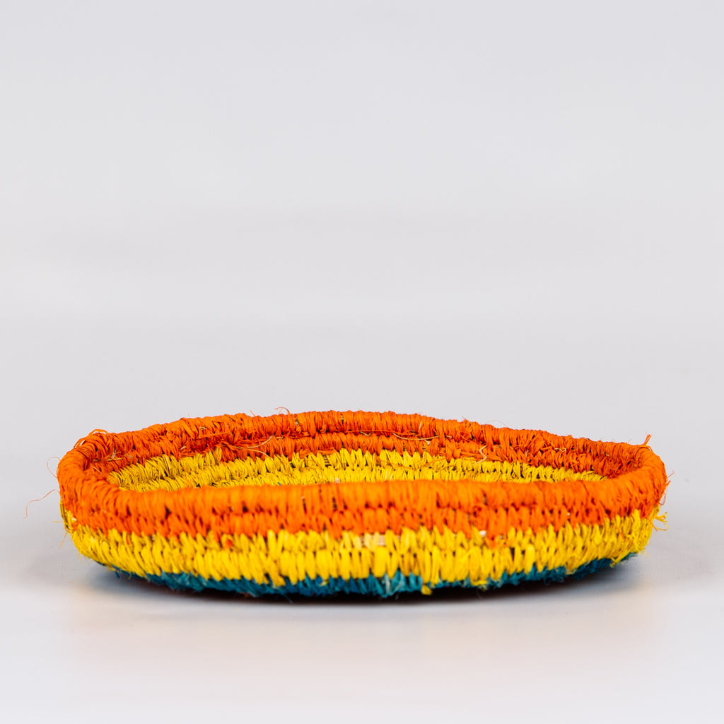 Side of grass woven basket in orange, yellow and blue colours.