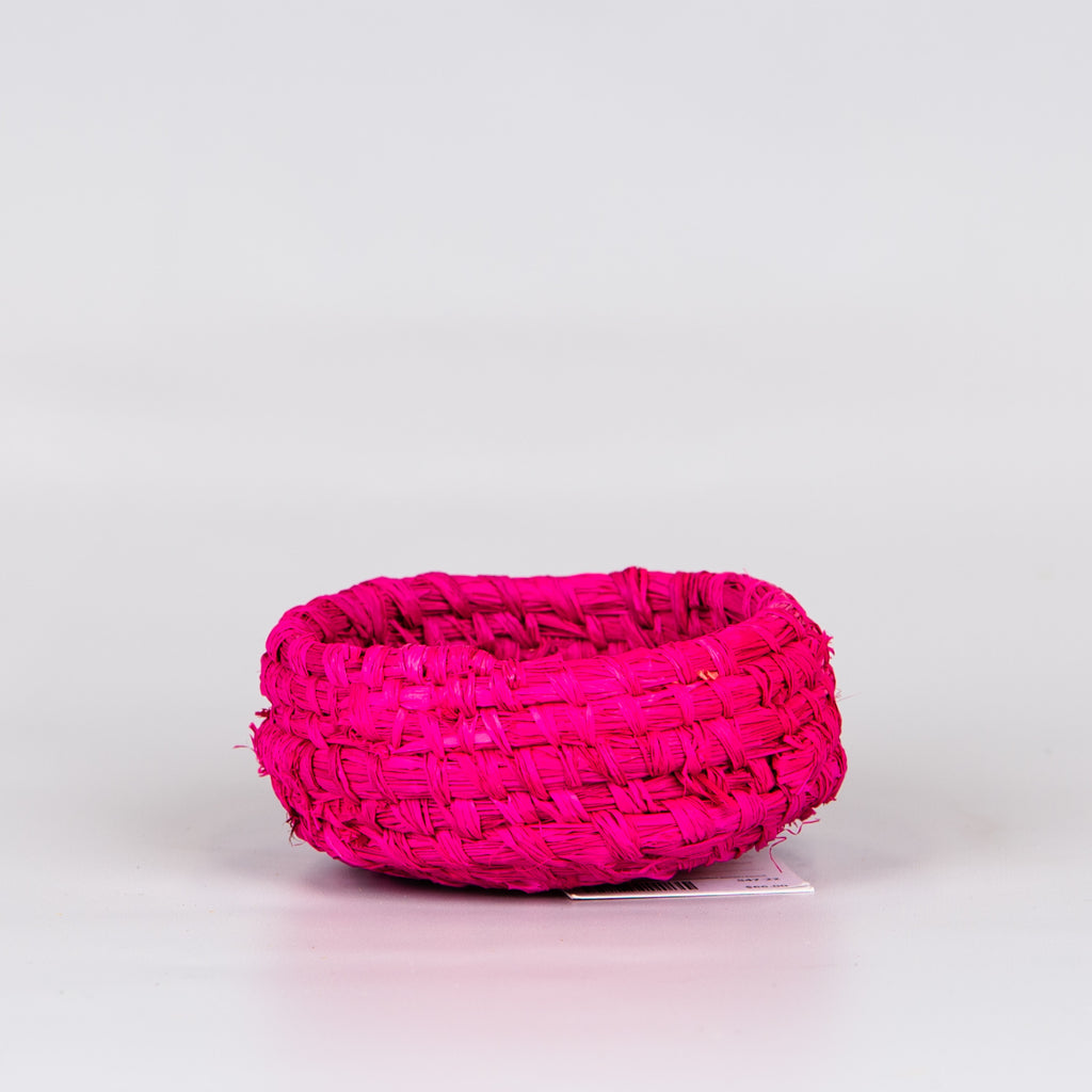 Side of grass woven basket in pink colours.
