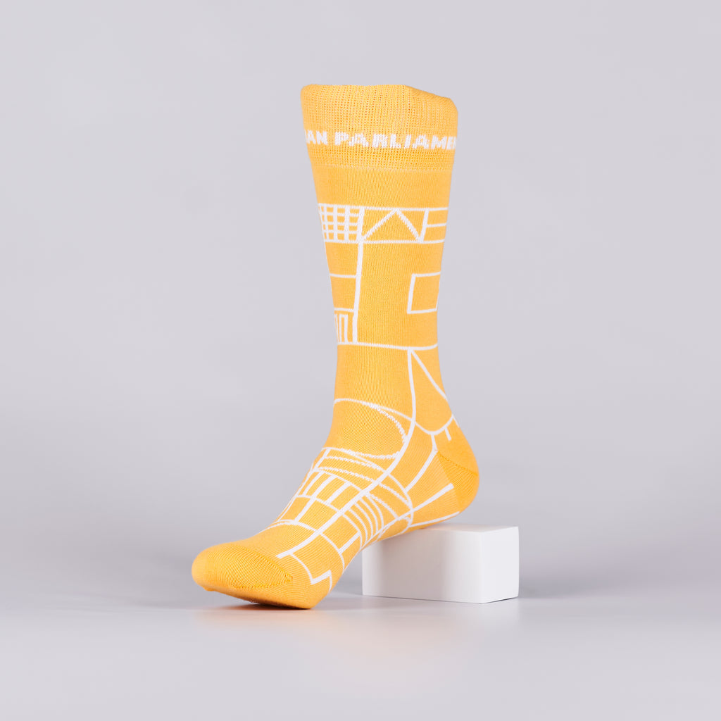 Yellow sock with a white geometric design on a foot mannequin. 