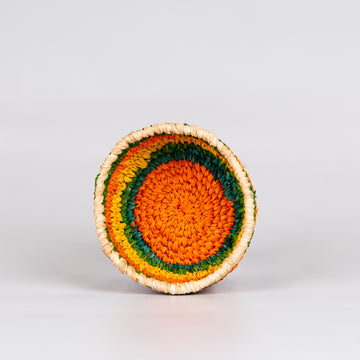 Inside of grass woven basket in orange, yellow and green colours.