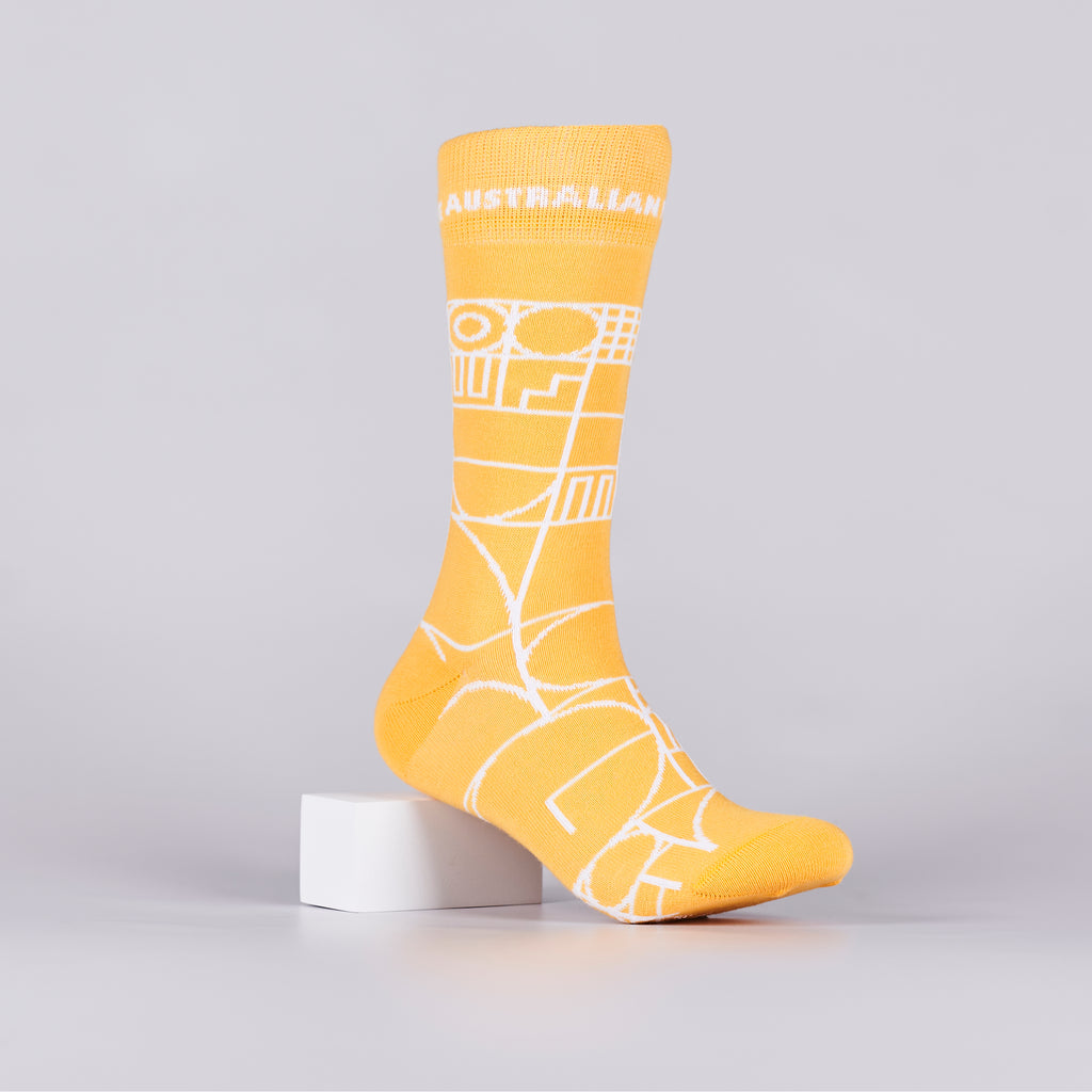 Yellow sock with a white geometric design on a foot mannequin. 
