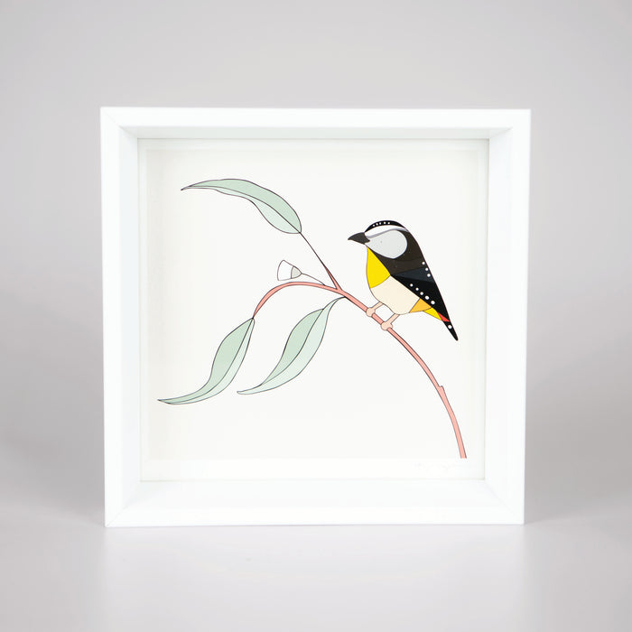 Artwork with a black and yellow bird on a branch with a white background in a white timber frame.