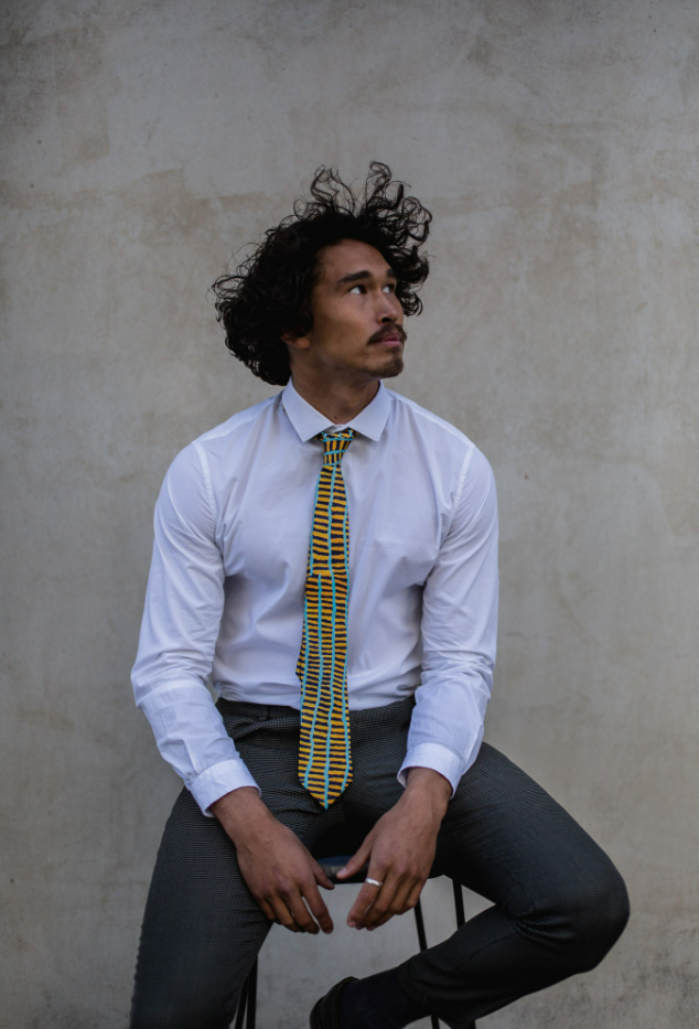 man wearing a rolled orange, dark blue and turquoise tie featuring uneven line design