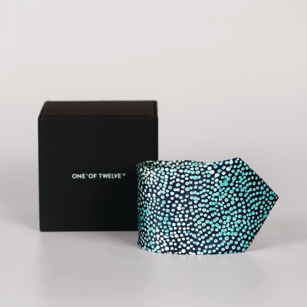 A rolled blue tie with dot detail and a black display box