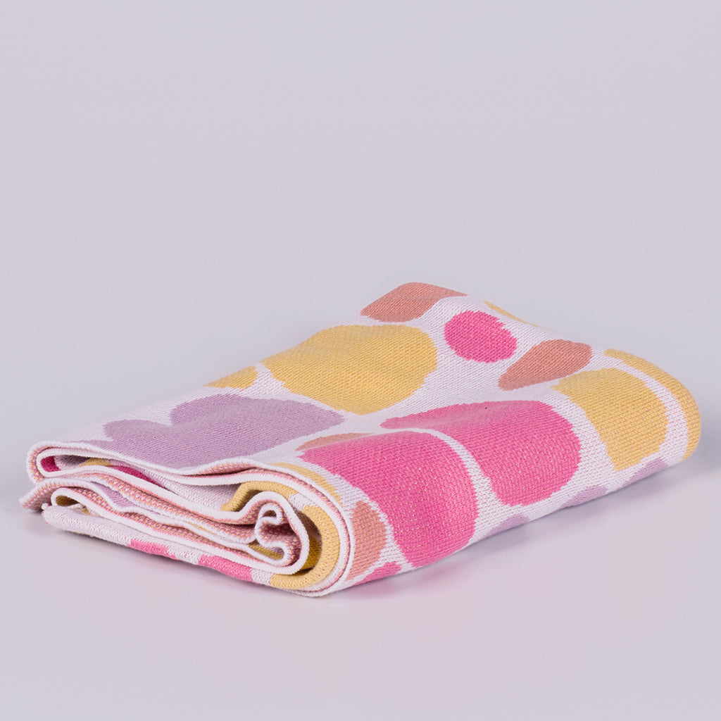 Folded blanket featuring coloured shapes. 