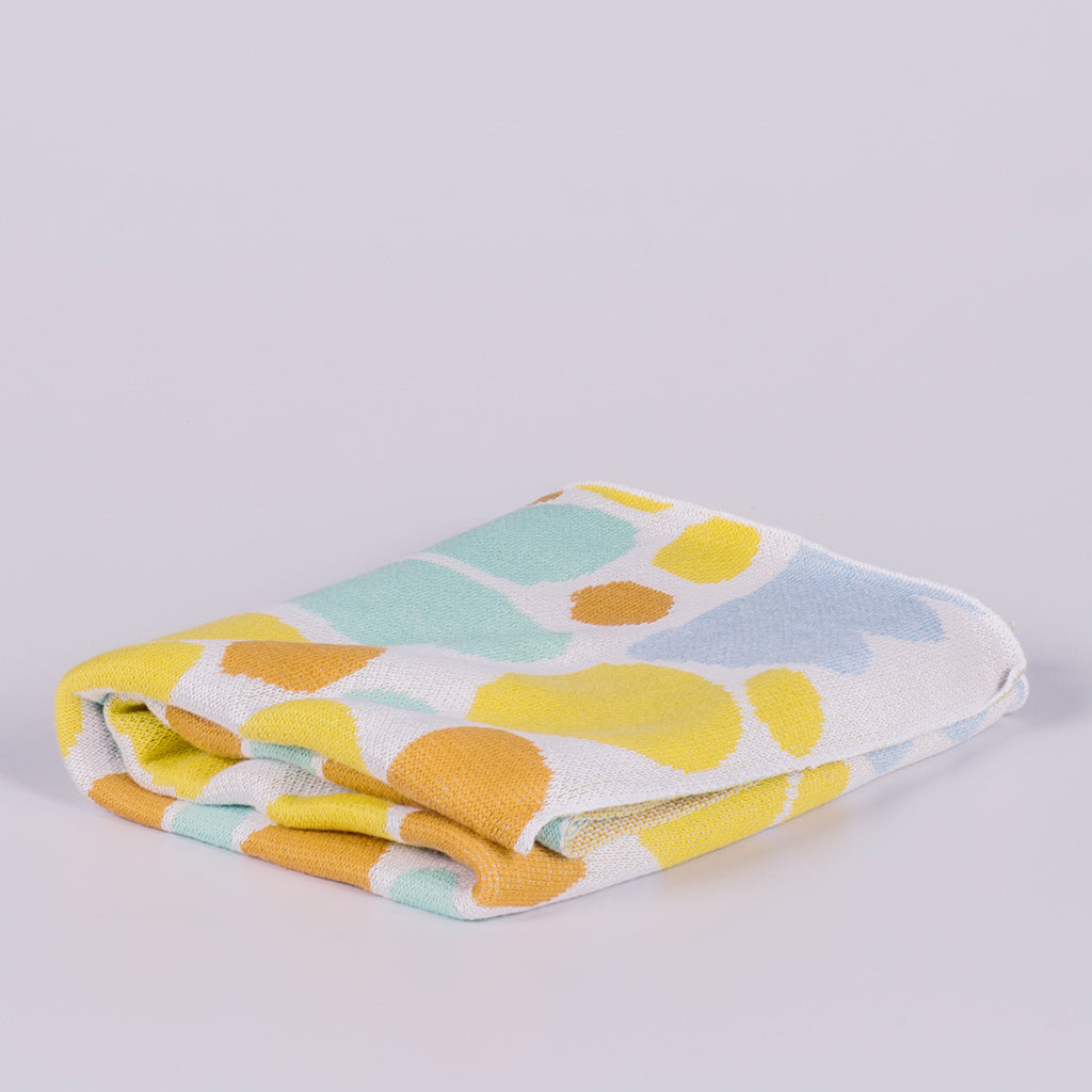 Folded blanket featuring coloured shapes. 