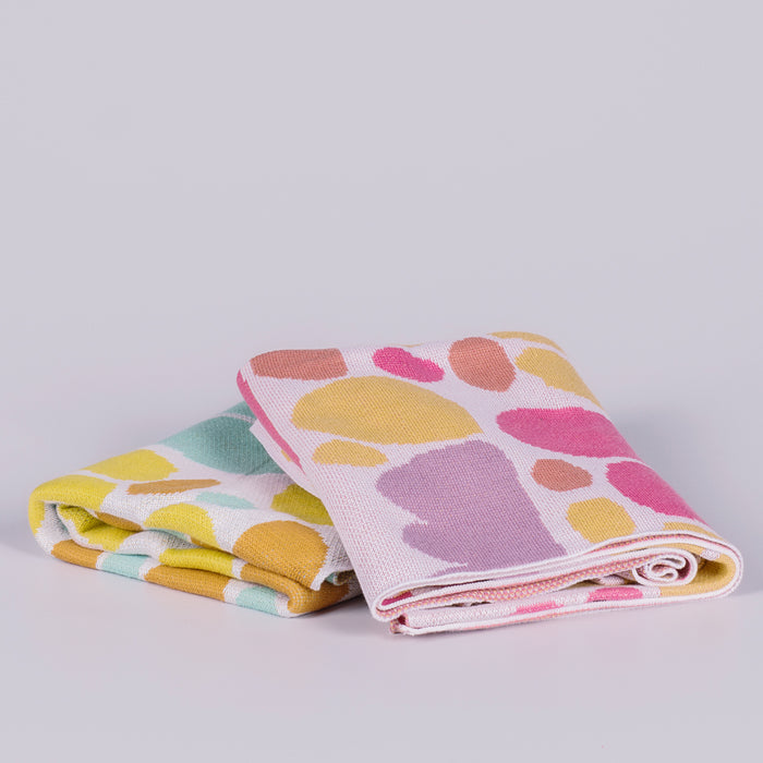 Two folded blankets featuring coloured shapes. 